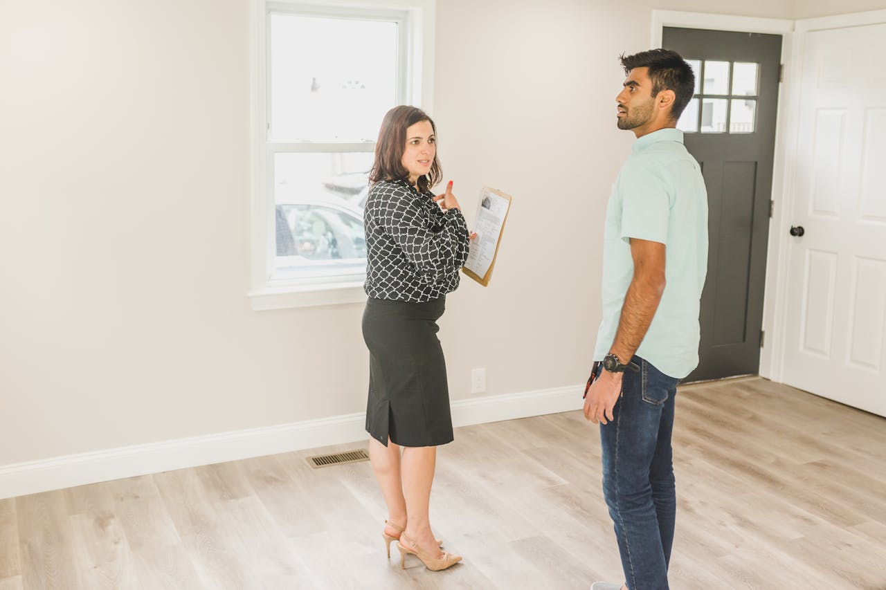 services-01 Real estate agent showing a modern home interior to a potential buyer.
